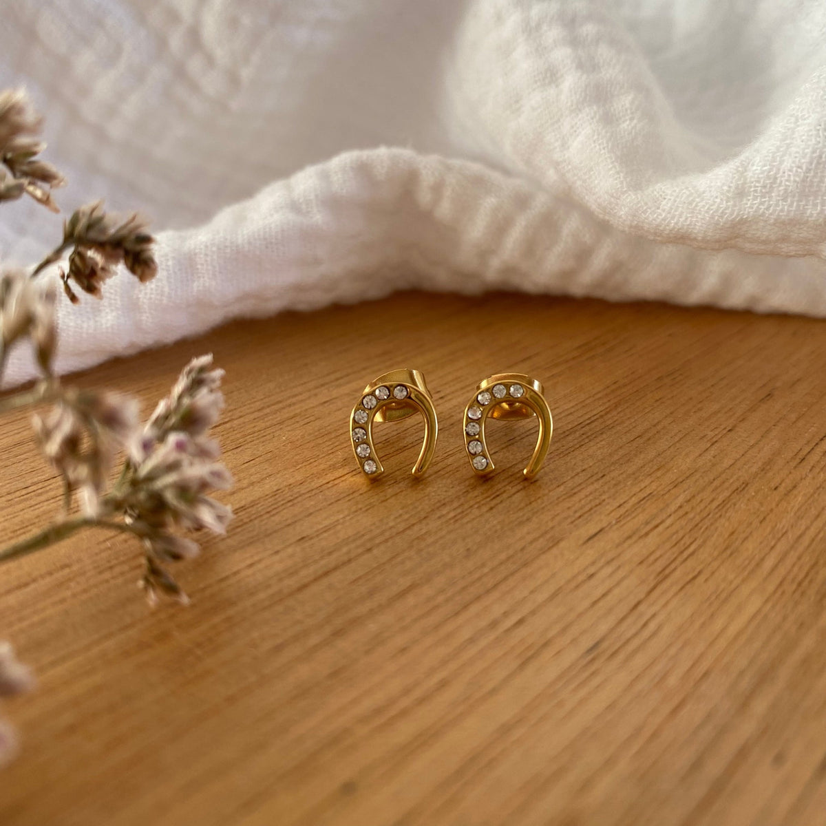 Equestrian Jewelry oorbellen Emy: hoefijzer-oorknopjes met strass-steentjes op één helft, in zilver of goud