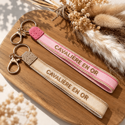 Equestrian Jewelry sleutelhanger Cavalière en or in stof met geborduurde tekst en goudkleurige ringen
