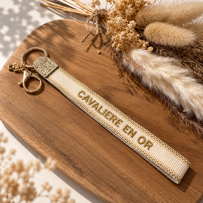 Equestrian Jewelry sleutelhanger Cavalière en or in stof met geborduurde tekst en goudkleurige ringen